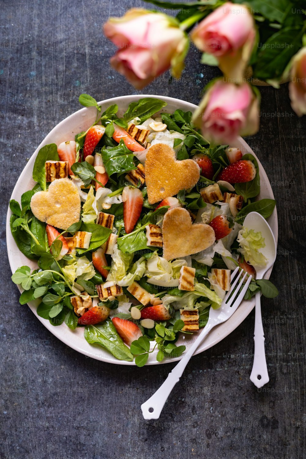 a white plate topped with a salad and a fork