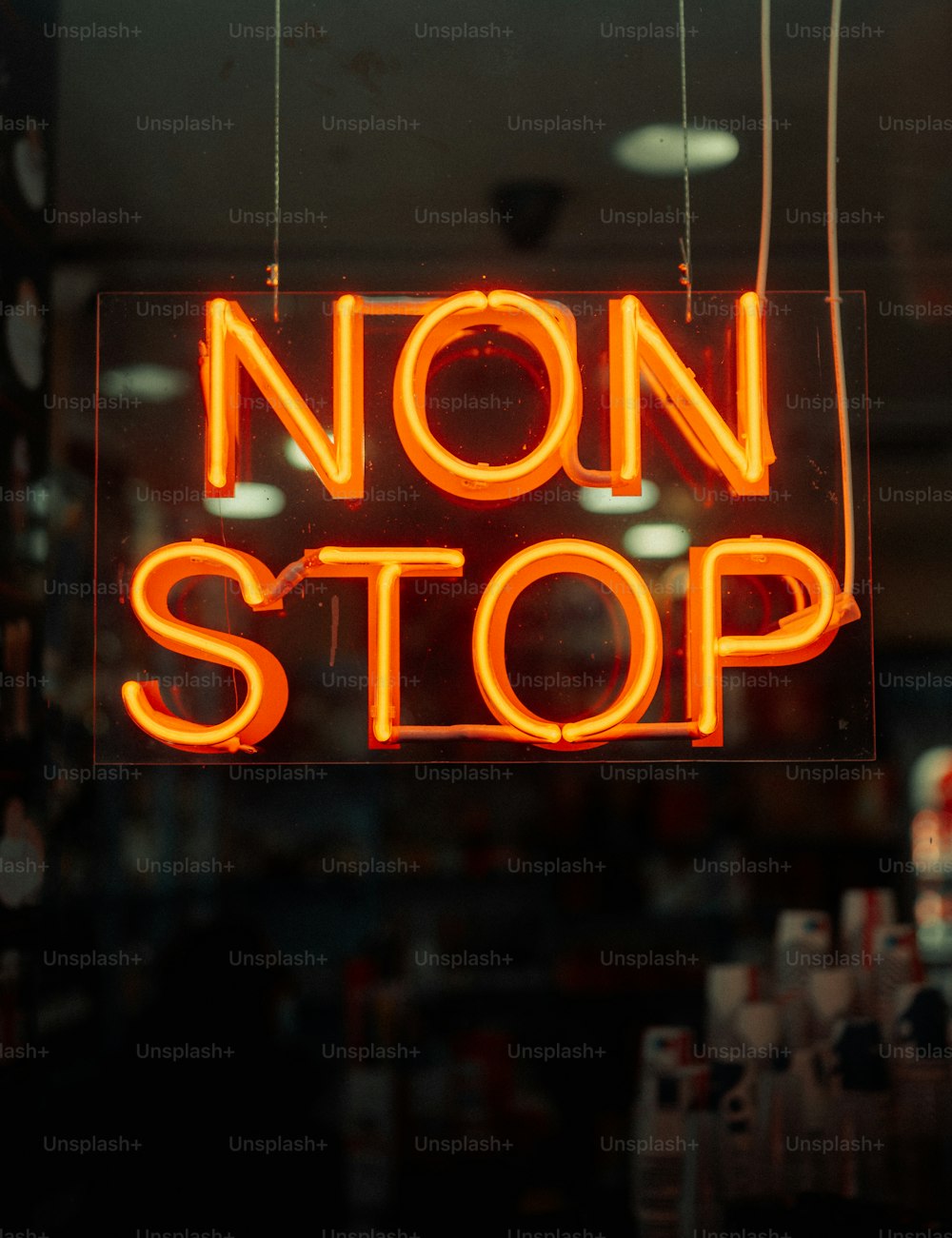 a neon sign that says non stop hanging from a window