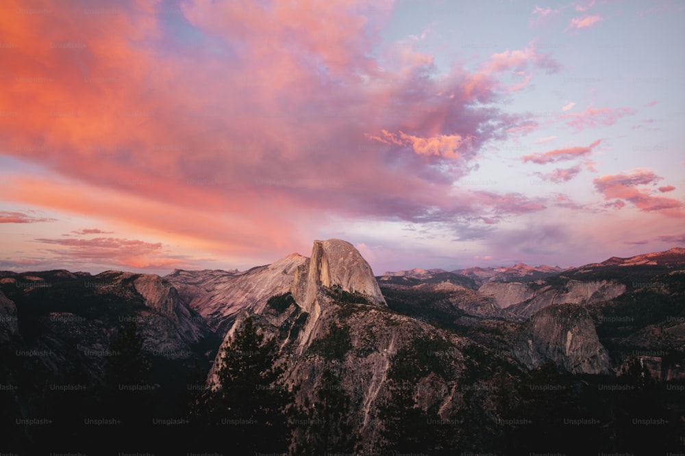 a sunset view of a mountain range with pink clouds