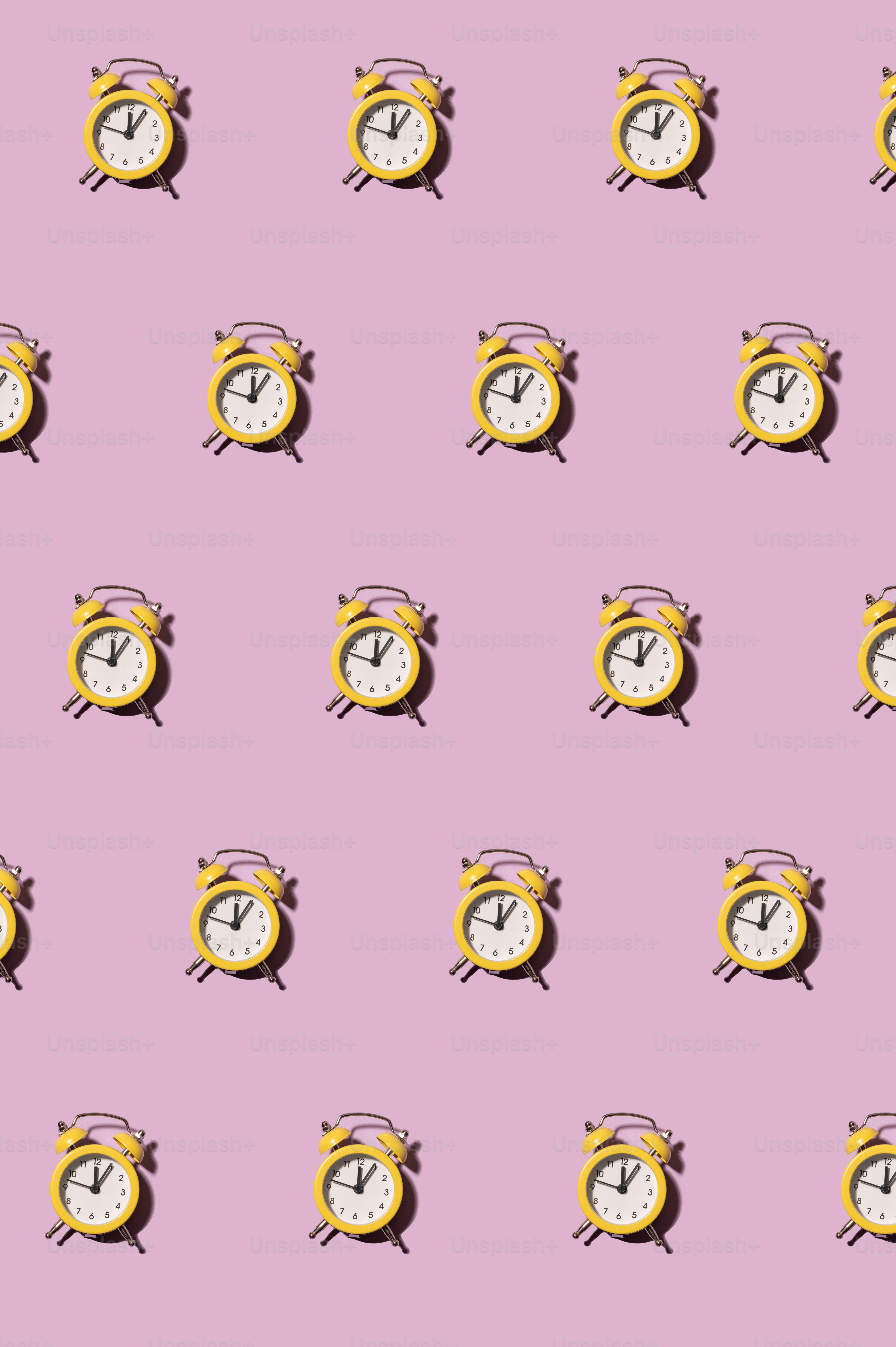 a pink background with a pattern of yellow and white clocks