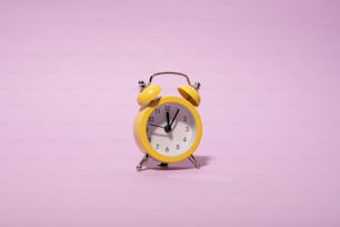 a yellow alarm clock on a purple background