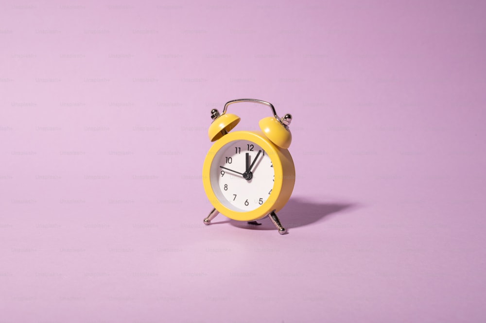 a yellow alarm clock on a purple background