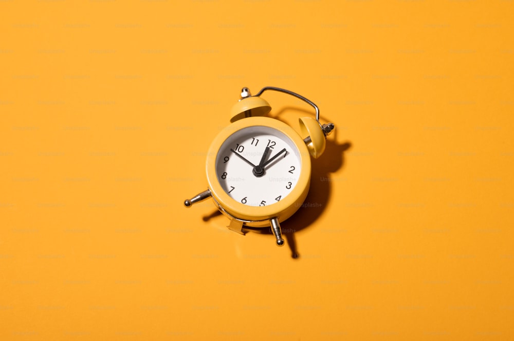 a yellow alarm clock sitting on top of a yellow wall