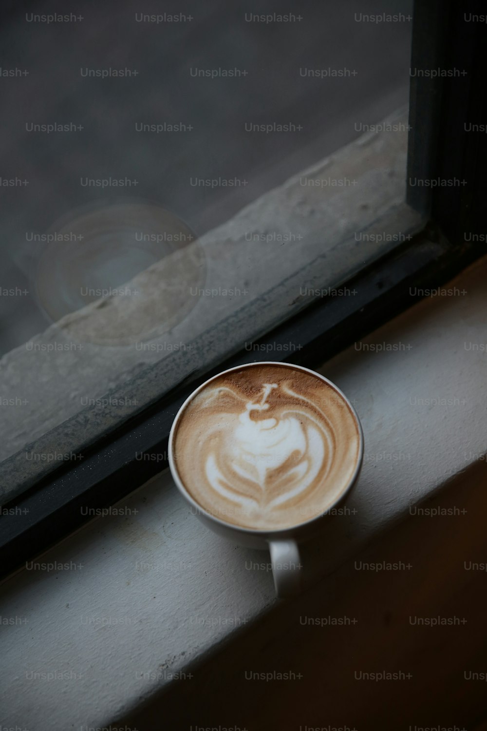 uma xícara de café sentada no peitoril de uma janela