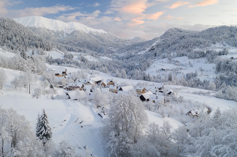 uma paisagem nevada com casas e árvores em primeiro plano