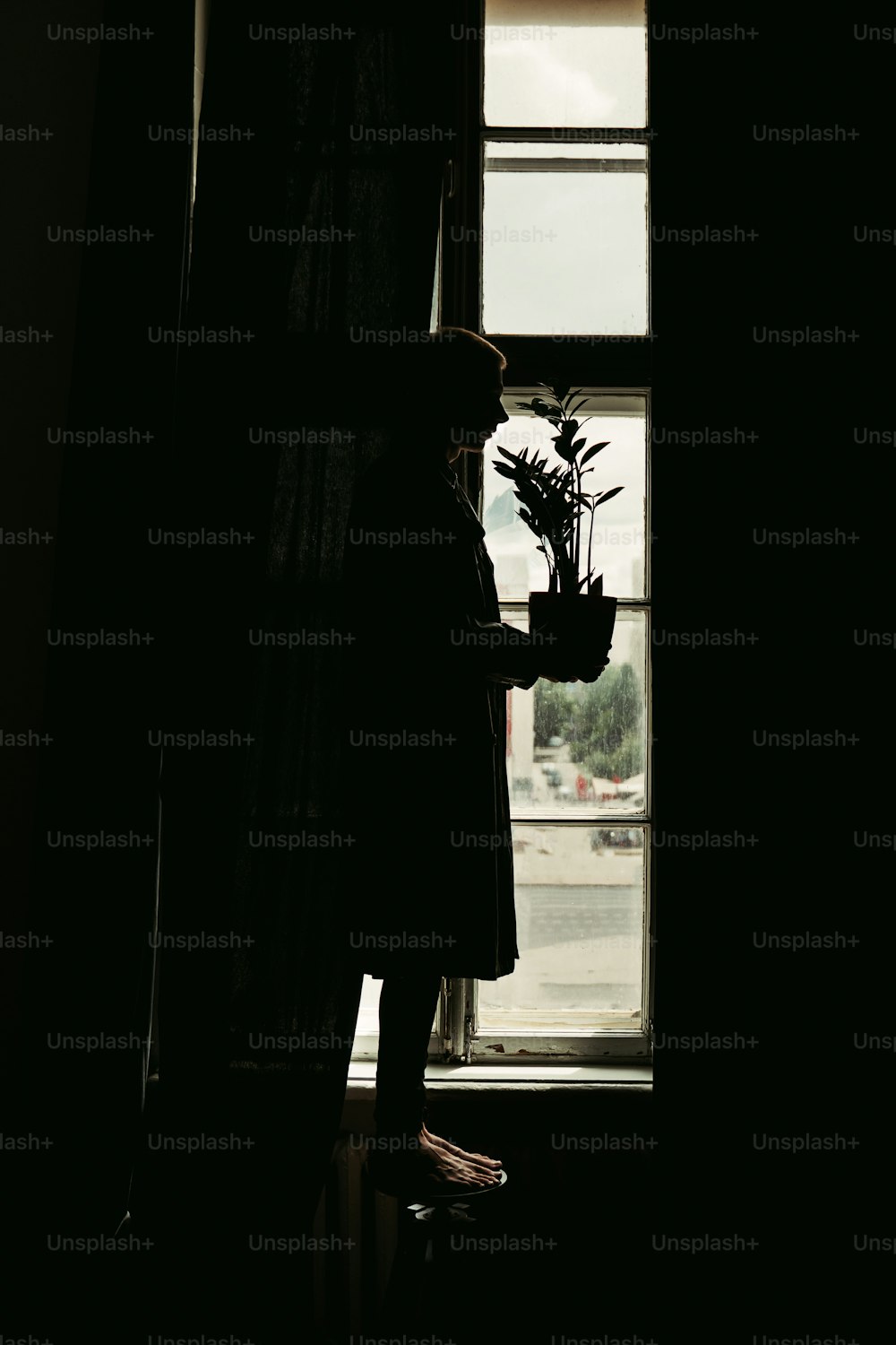 Eine Person, die vor einem Fenster steht und einen Blumenstrauß hält