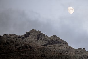 Une pleine lune est vue au-dessus d’une montagne rocheuse