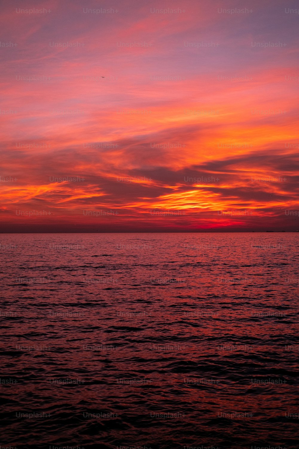 un tramonto su uno specchio d'acqua con una barca in lontananza
