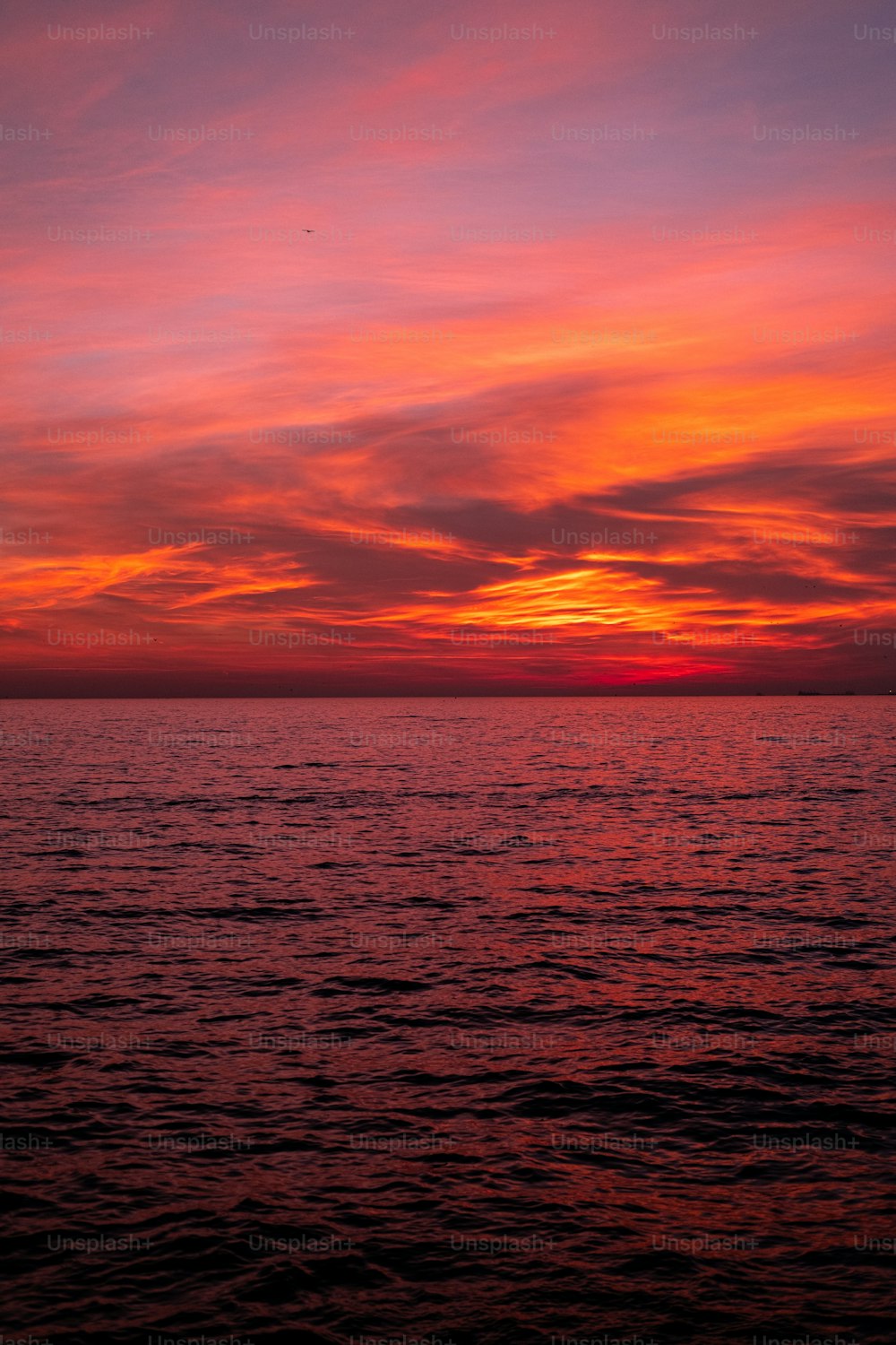 a sunset over a body of water with a boat in the distance