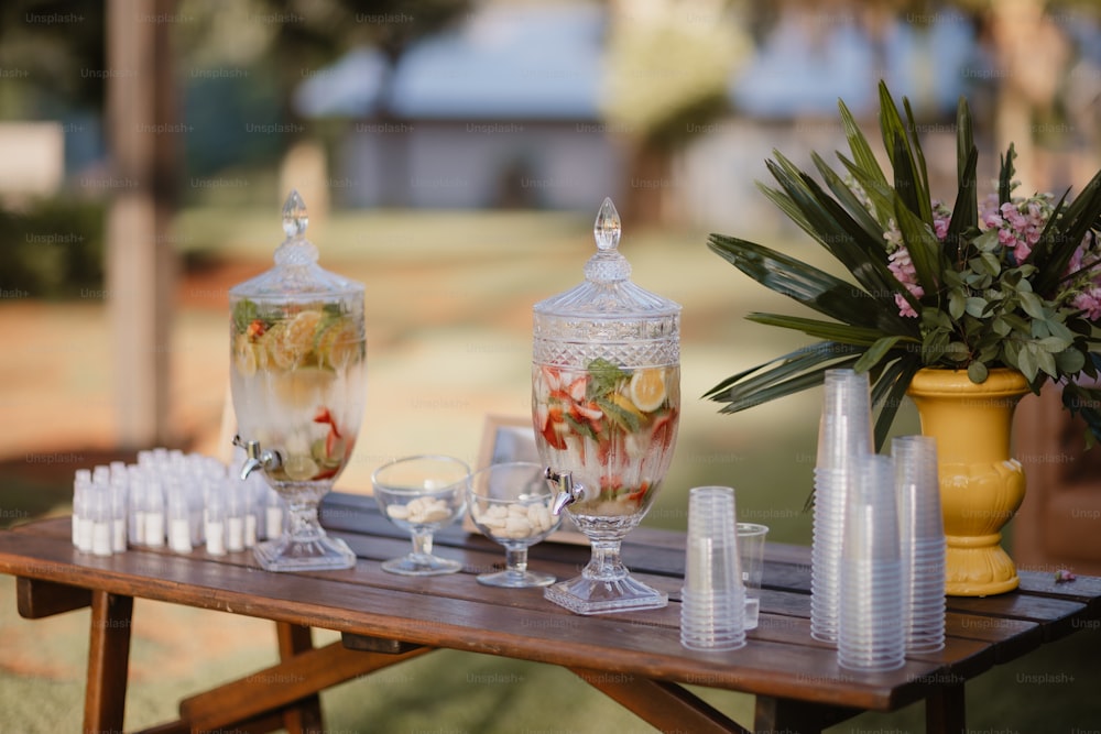 a wooden table topped with lots of glasses and vases