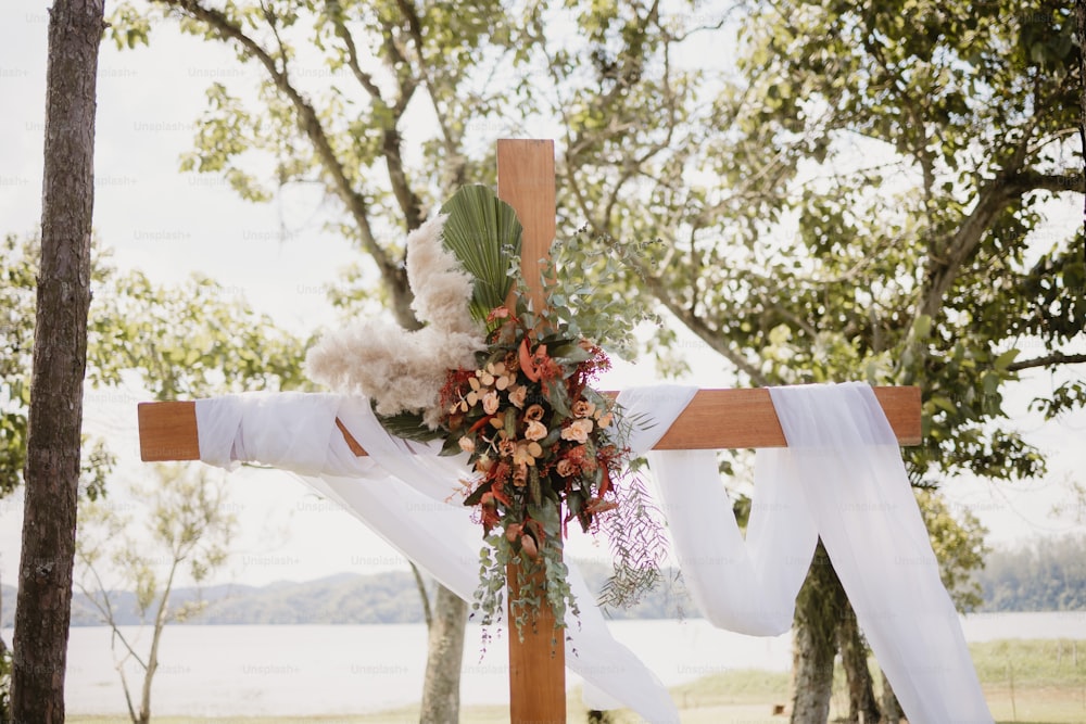 a wooden cross decorated with flowers and greenery