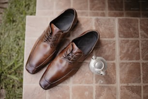 Un paio di scarpe marroni sedute sopra un pavimento di piastrelle