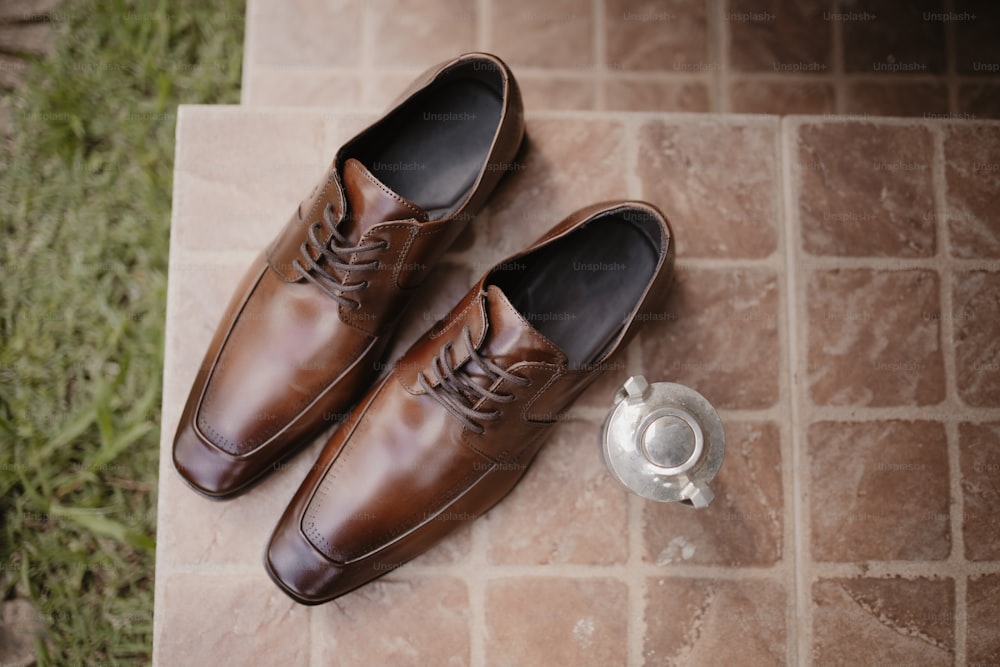 a pair of brown shoes sitting on top of a tile floor