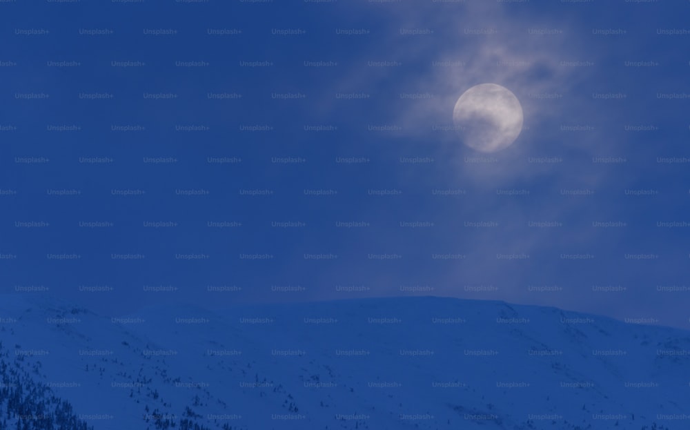 Una luna piena è vista sopra una montagna innevata