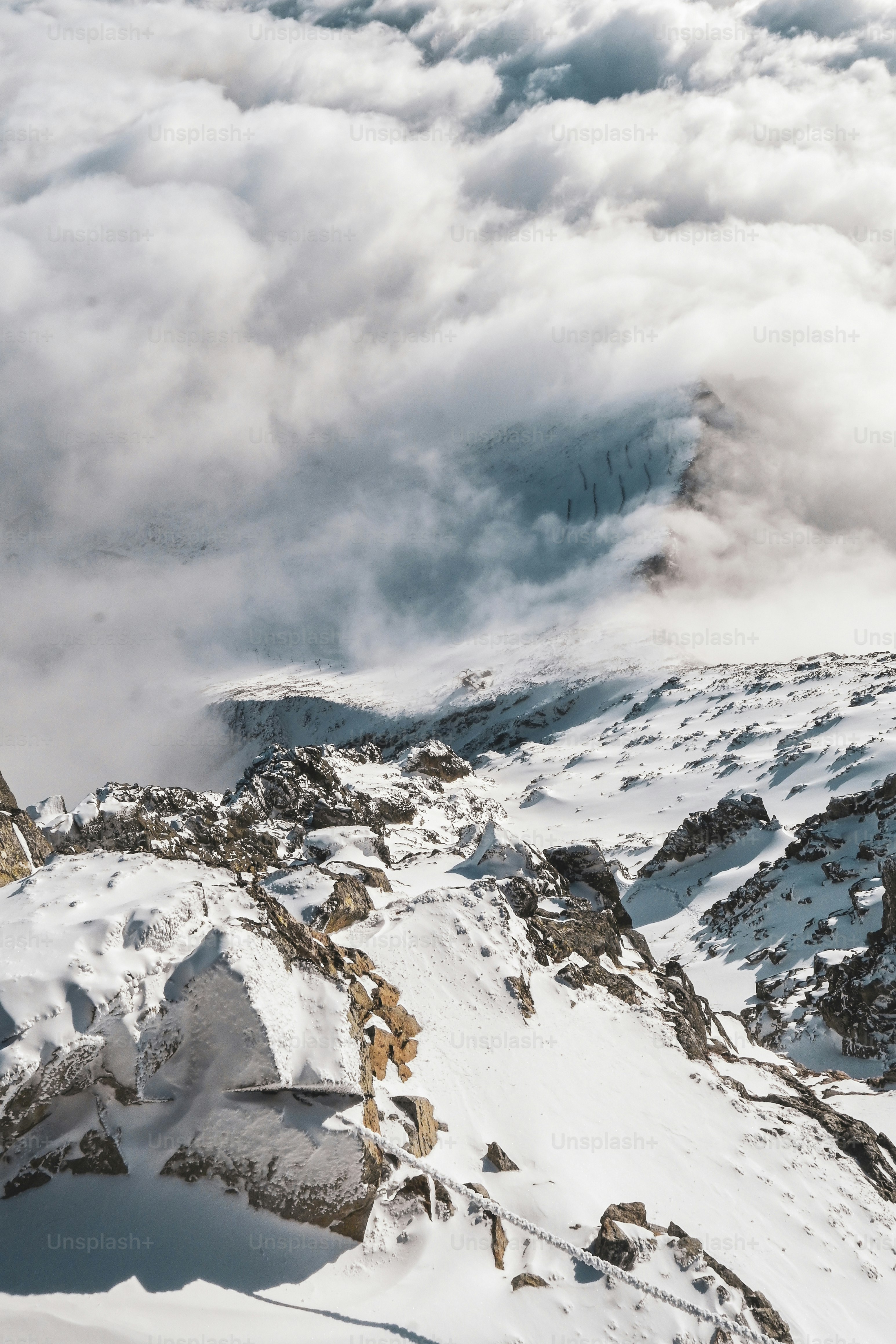 a mountain covered in snow and clouds in the distance
