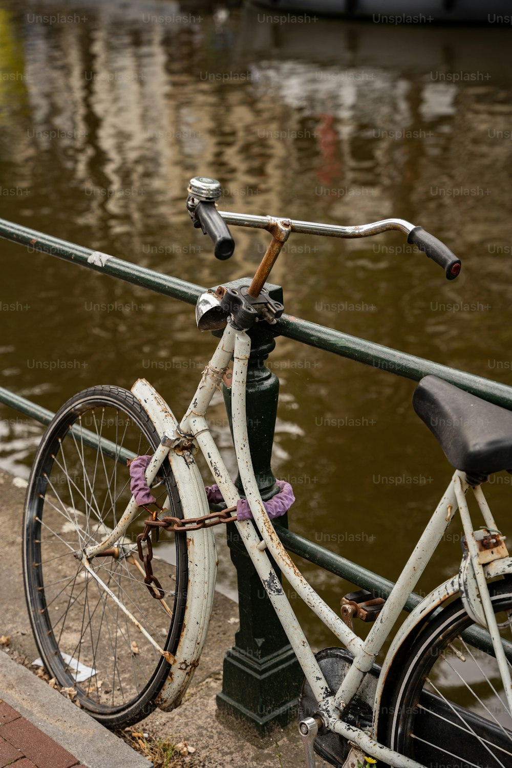 uma bicicleta estacionada ao lado de um poste perto de um corpo de água
