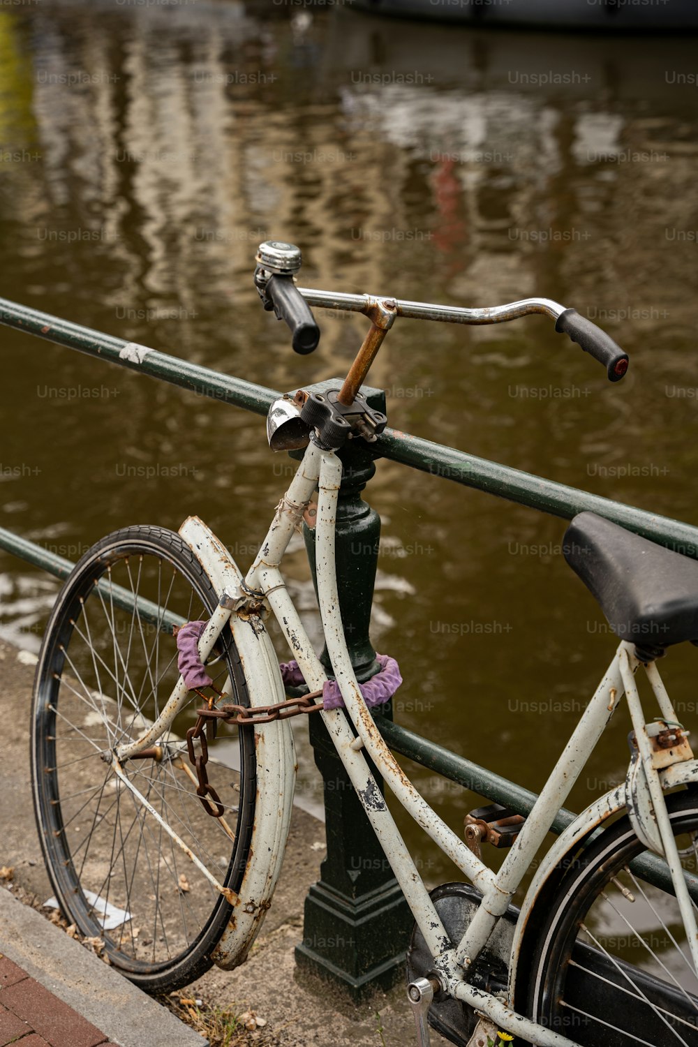 una bicicleta estacionada junto a un poste cerca de un cuerpo de agua