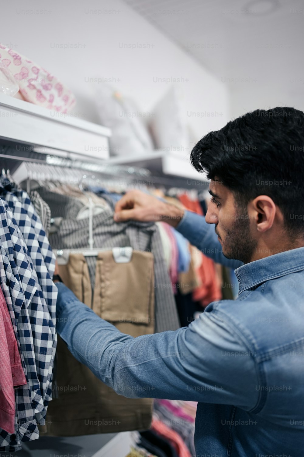 a man is looking at clothes on a rack