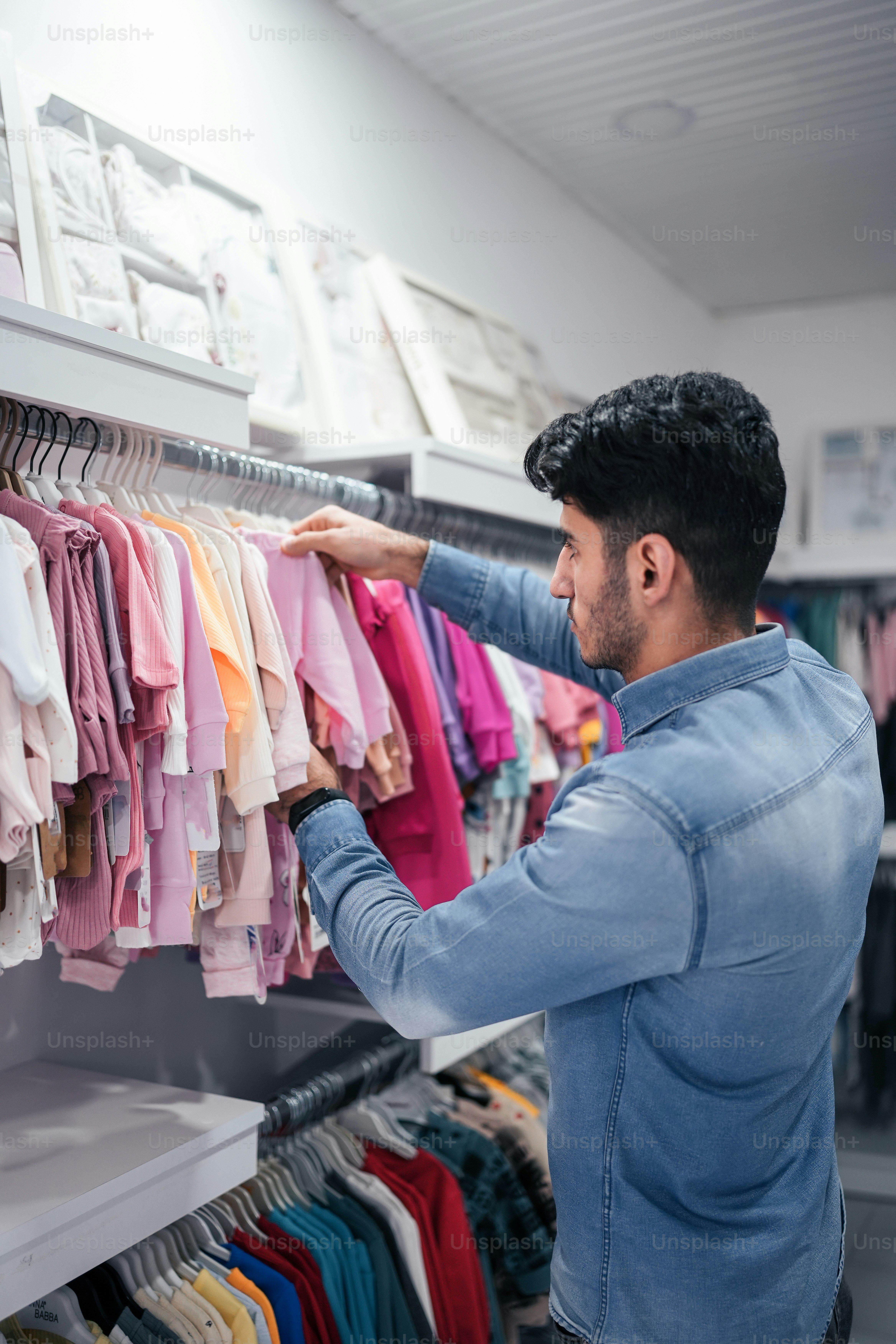 a man looking at a rack of shirts