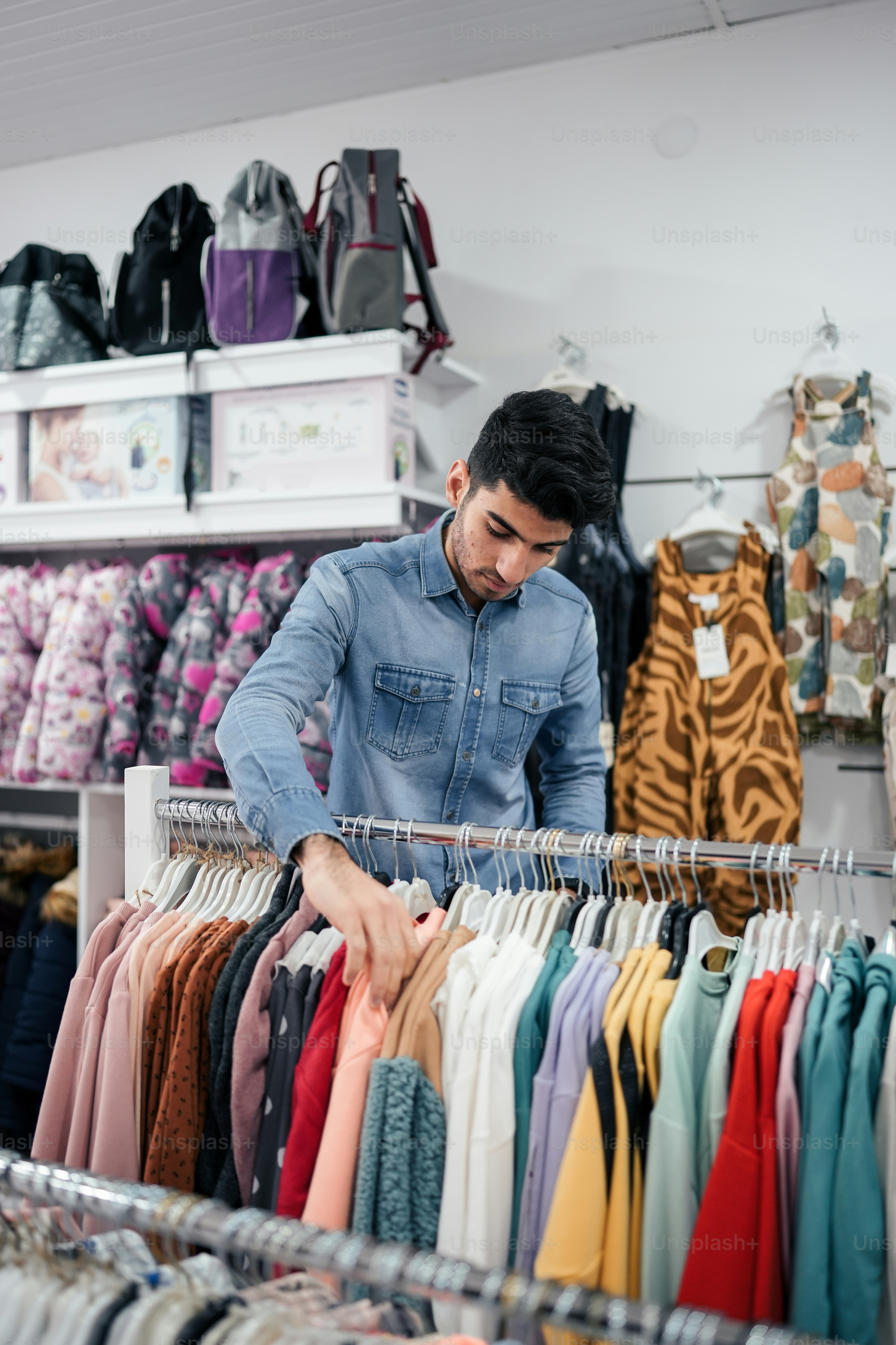 a man standing in front of a rack of shirts