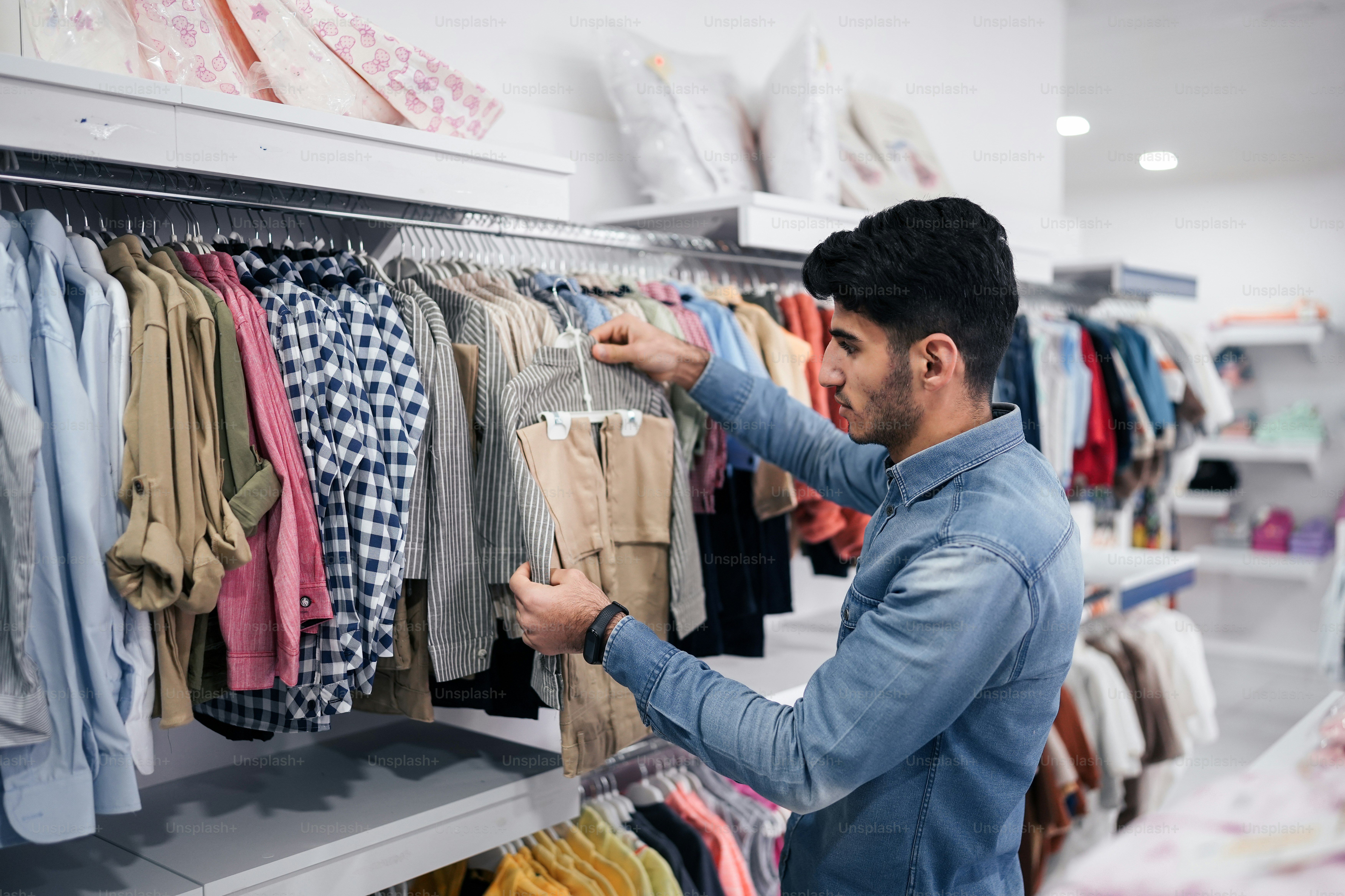 a man looking at a rack of shirts in a store