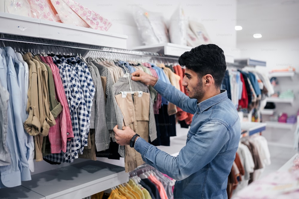 um homem olhando para um rack de camisas em uma loja