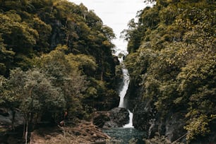 a man riding a boat down a river next to a waterfall