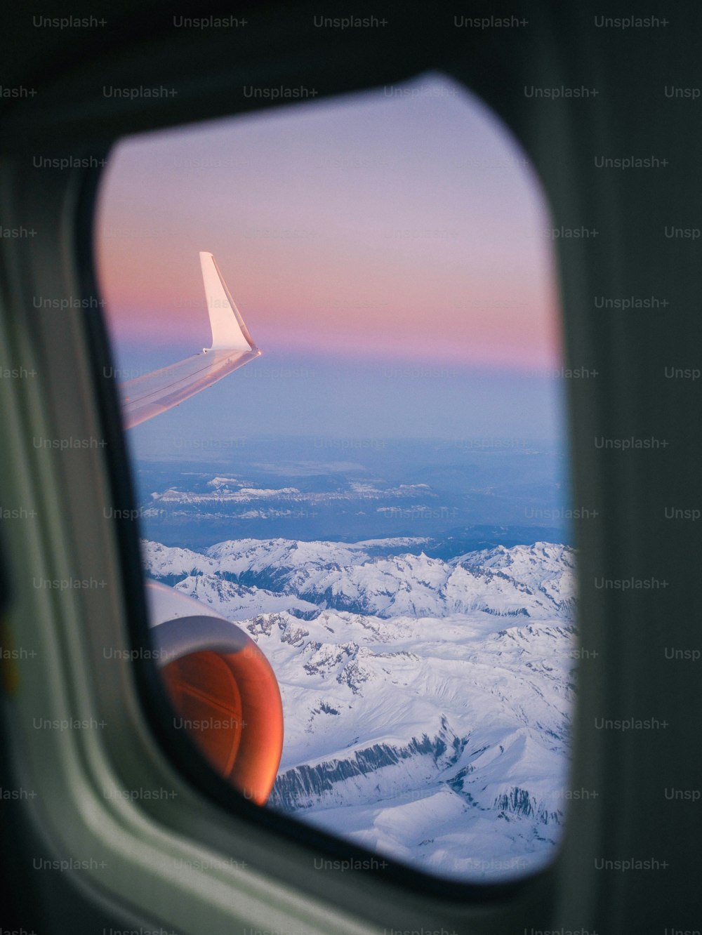 雪に覆われた山々の景色を望む飛行機の窓
