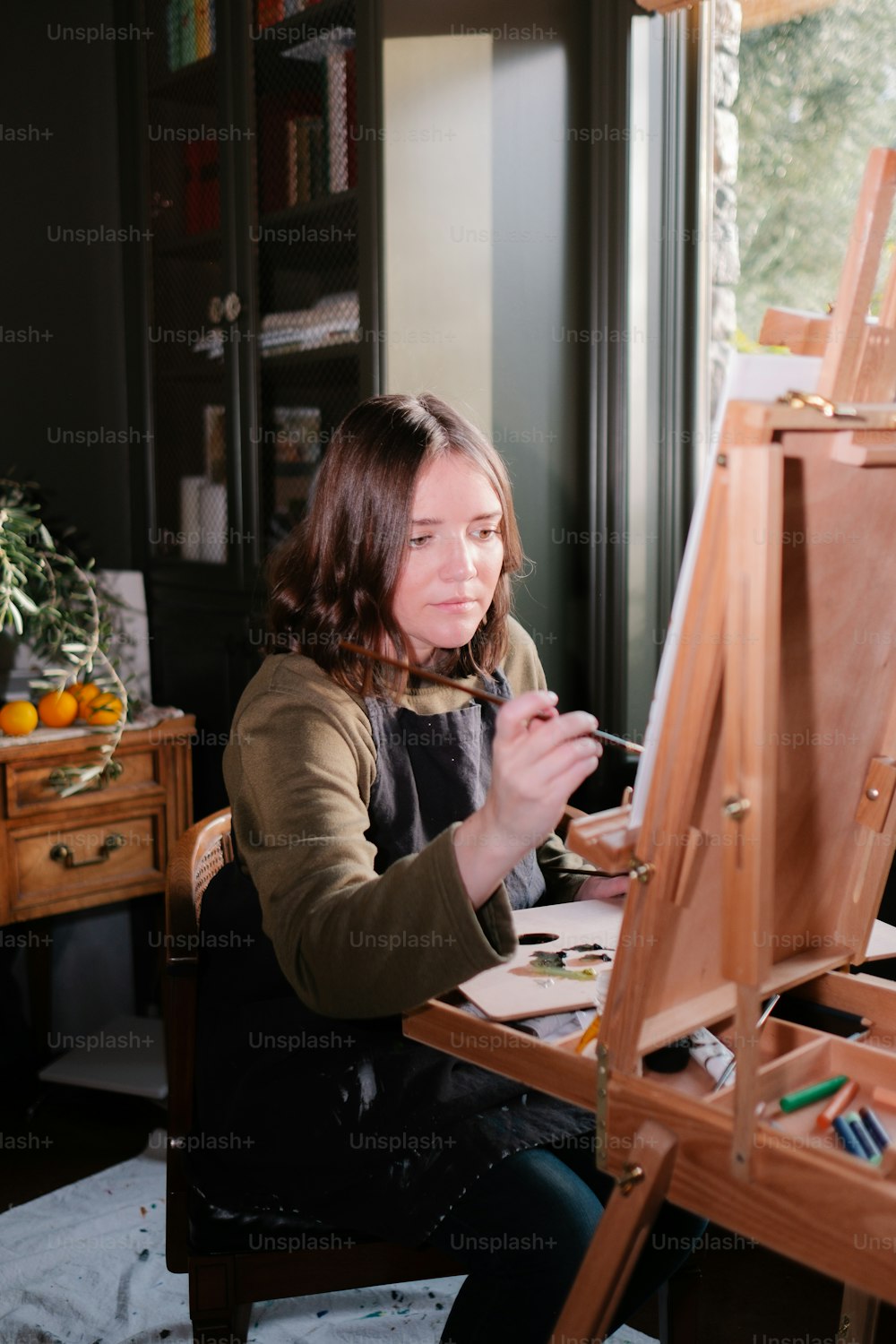a woman sitting in front of a easel painting