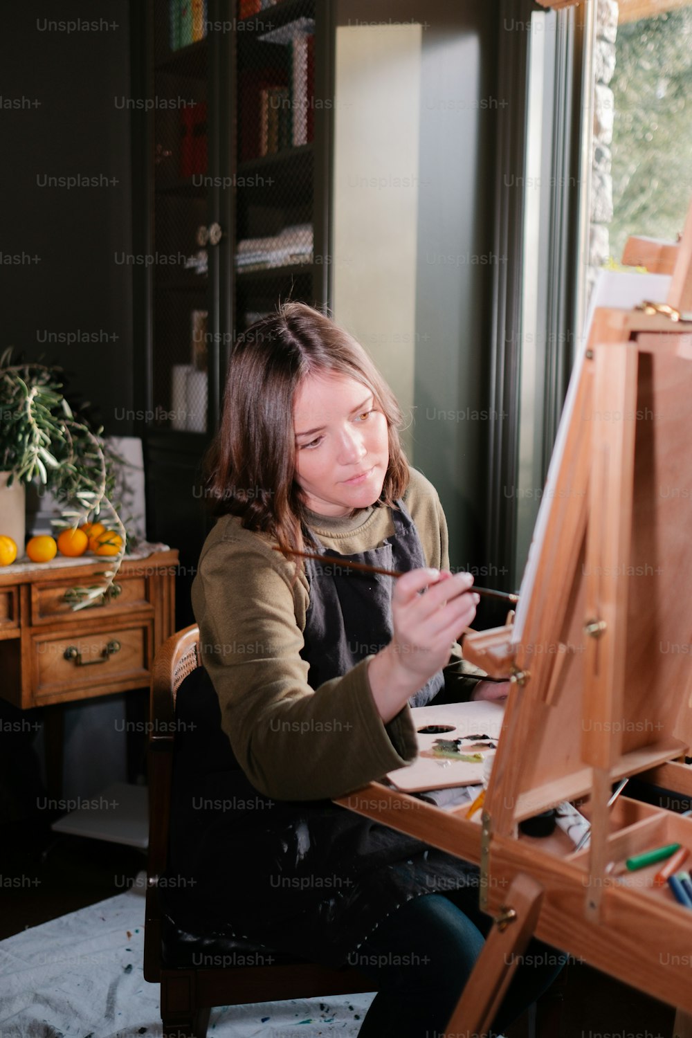 a woman sitting in front of a easel painting