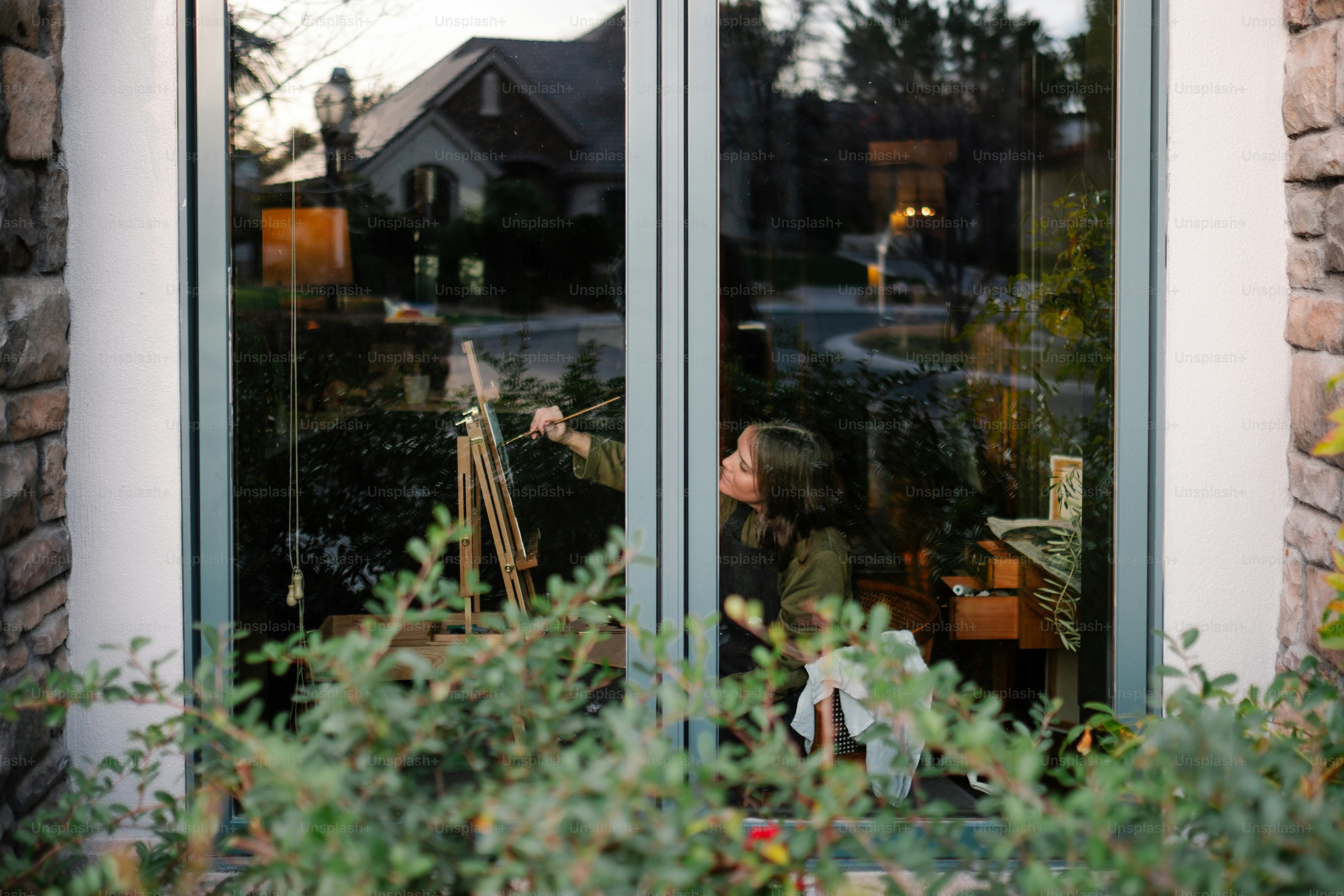Una mujer está pintando fuera de una ventana