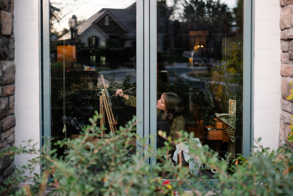 窓の外で絵を描いている女性