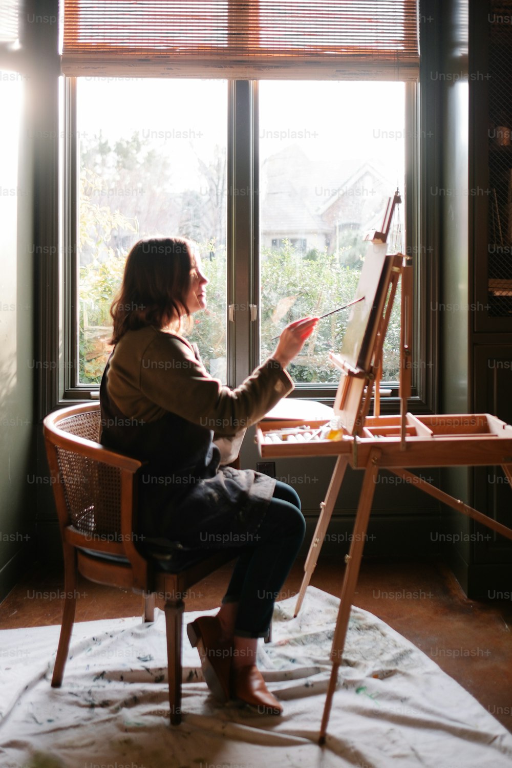 une femme assise sur une chaise devant une fenêtre