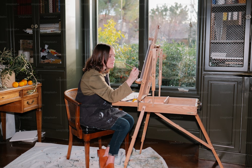 a woman sitting at a table with an easel