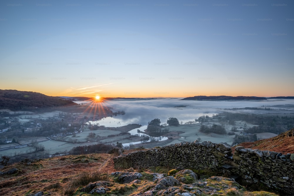 the sun is setting over a foggy valley