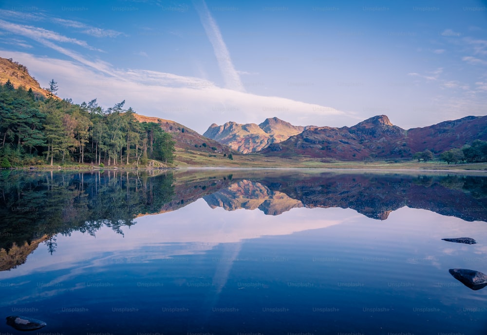 um lago cercado por montanhas e árvores sob um céu azul