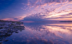 a body of water with a sky filled with clouds