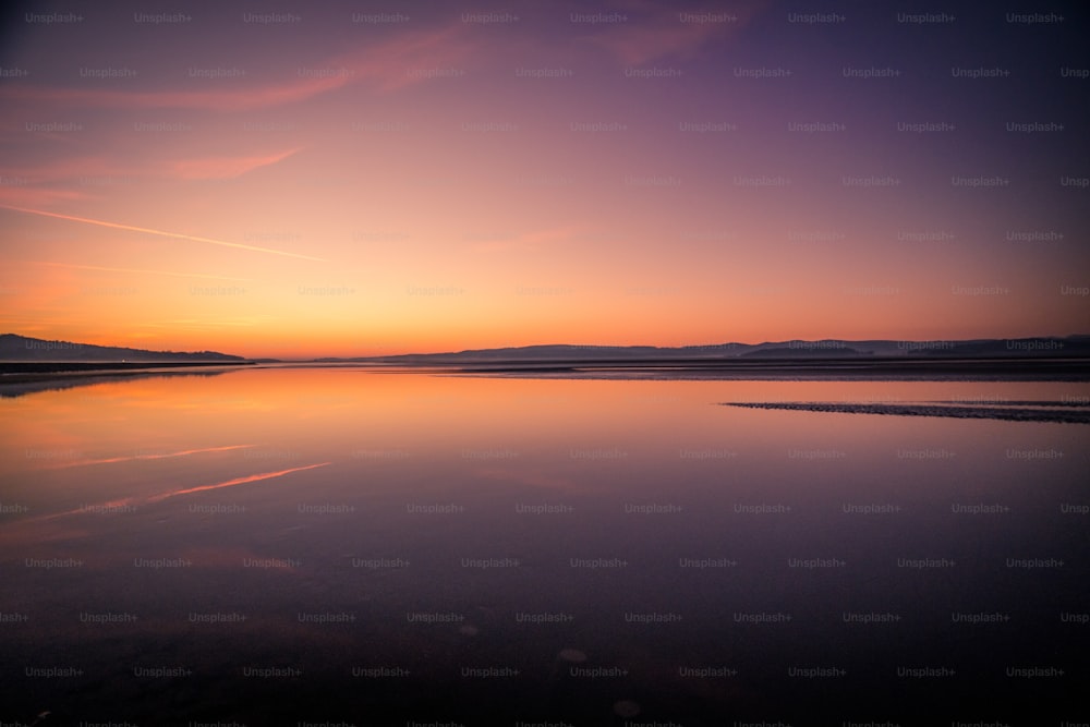 a large body of water sitting under a purple sky