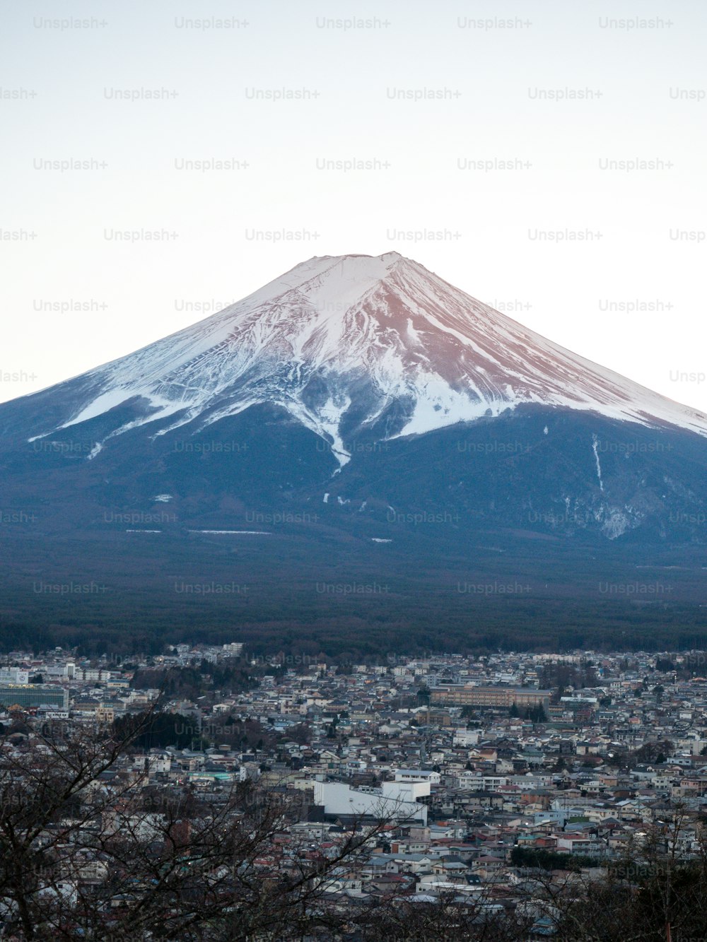 a large snow covered mountain towering over a city