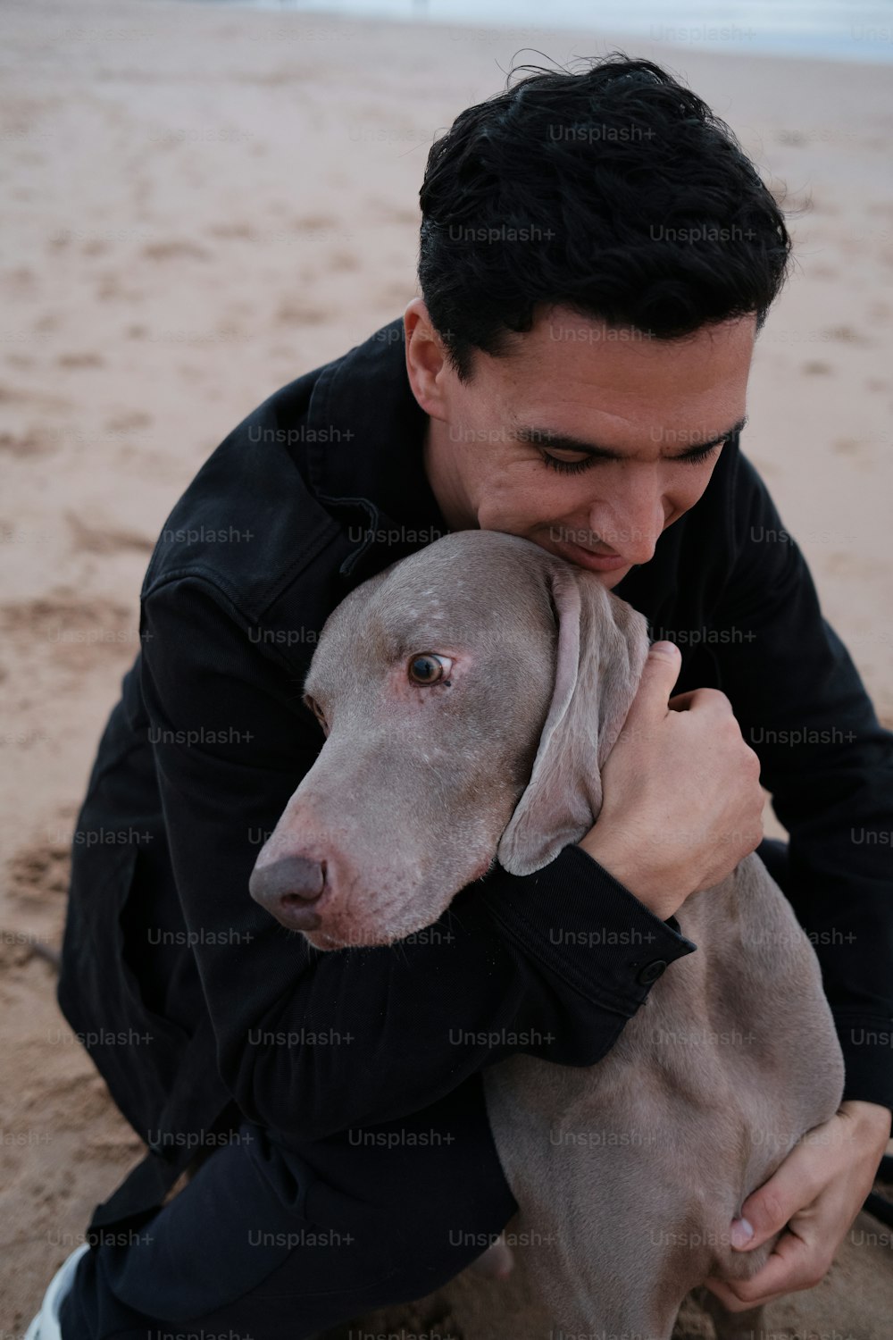 Ein Mann, der einen Hund am Strand hält