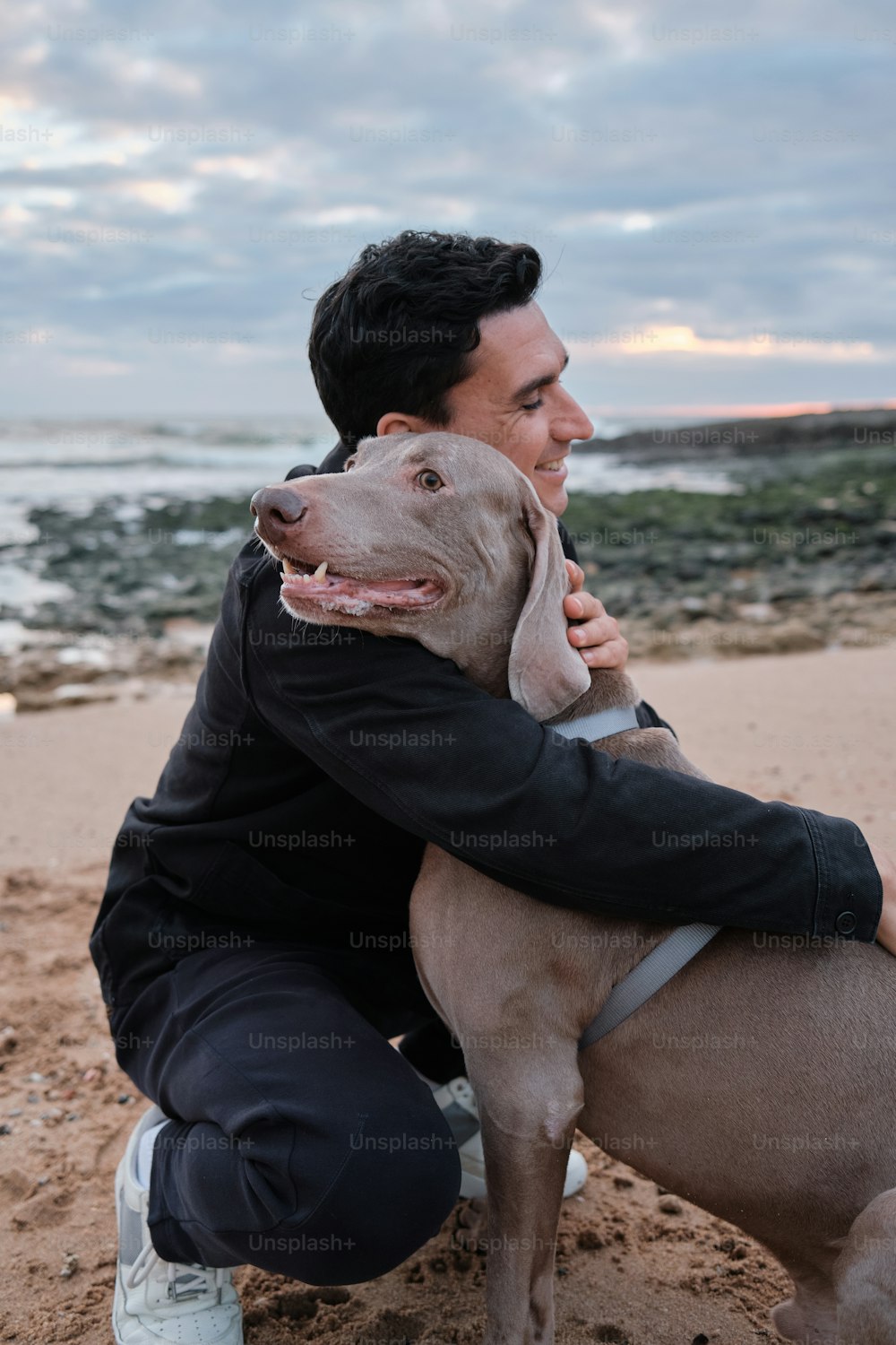 a man holding a dog on the beach