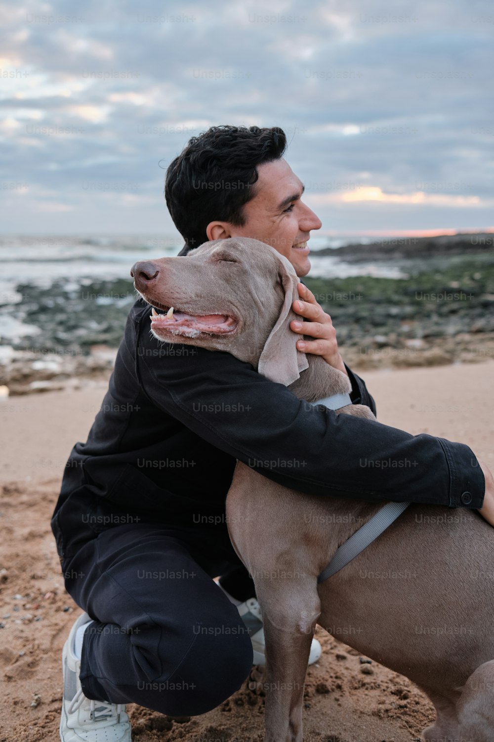 Un hombre sosteniendo un perro en la playa