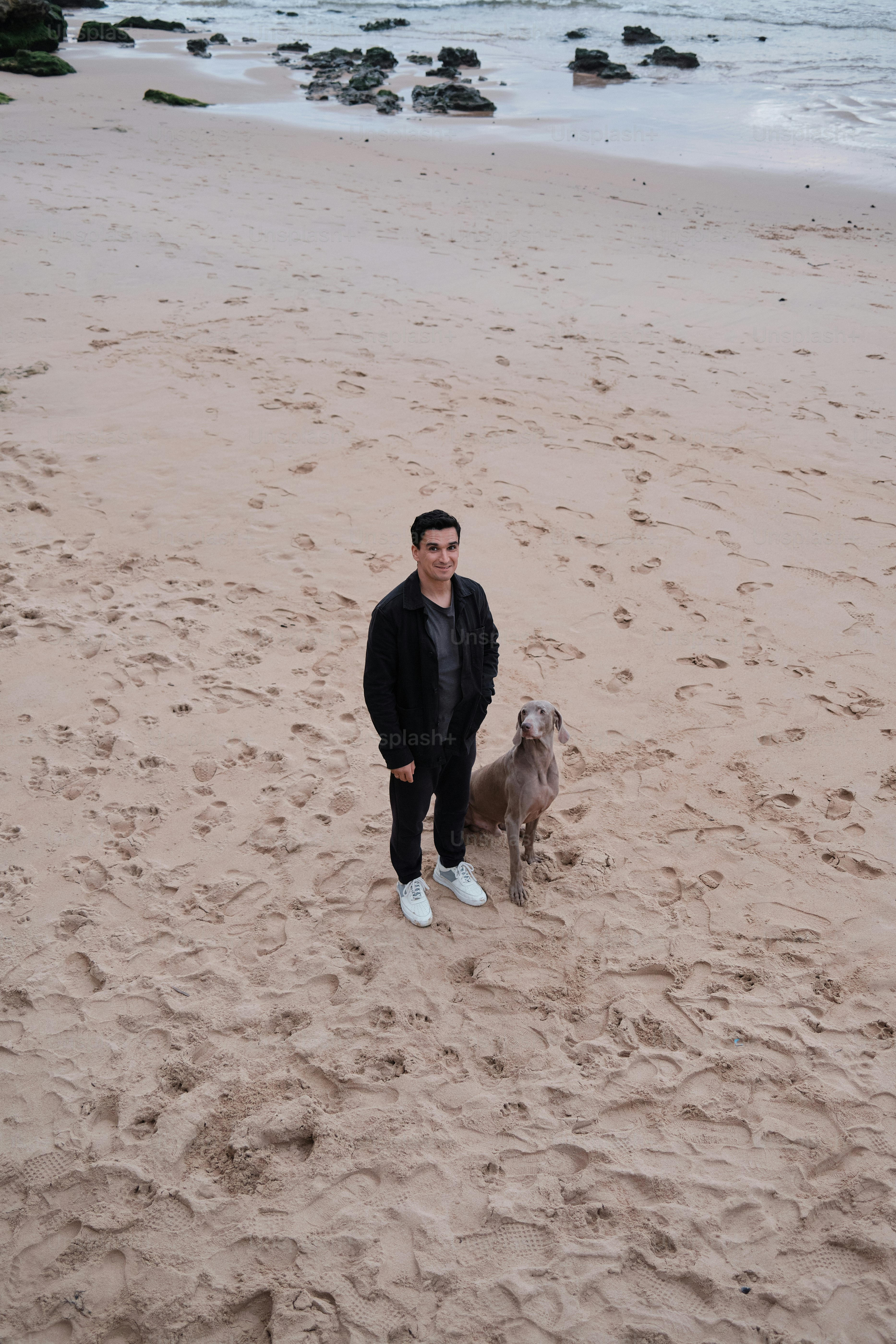 Ein Mann steht am Strand neben einem Hund