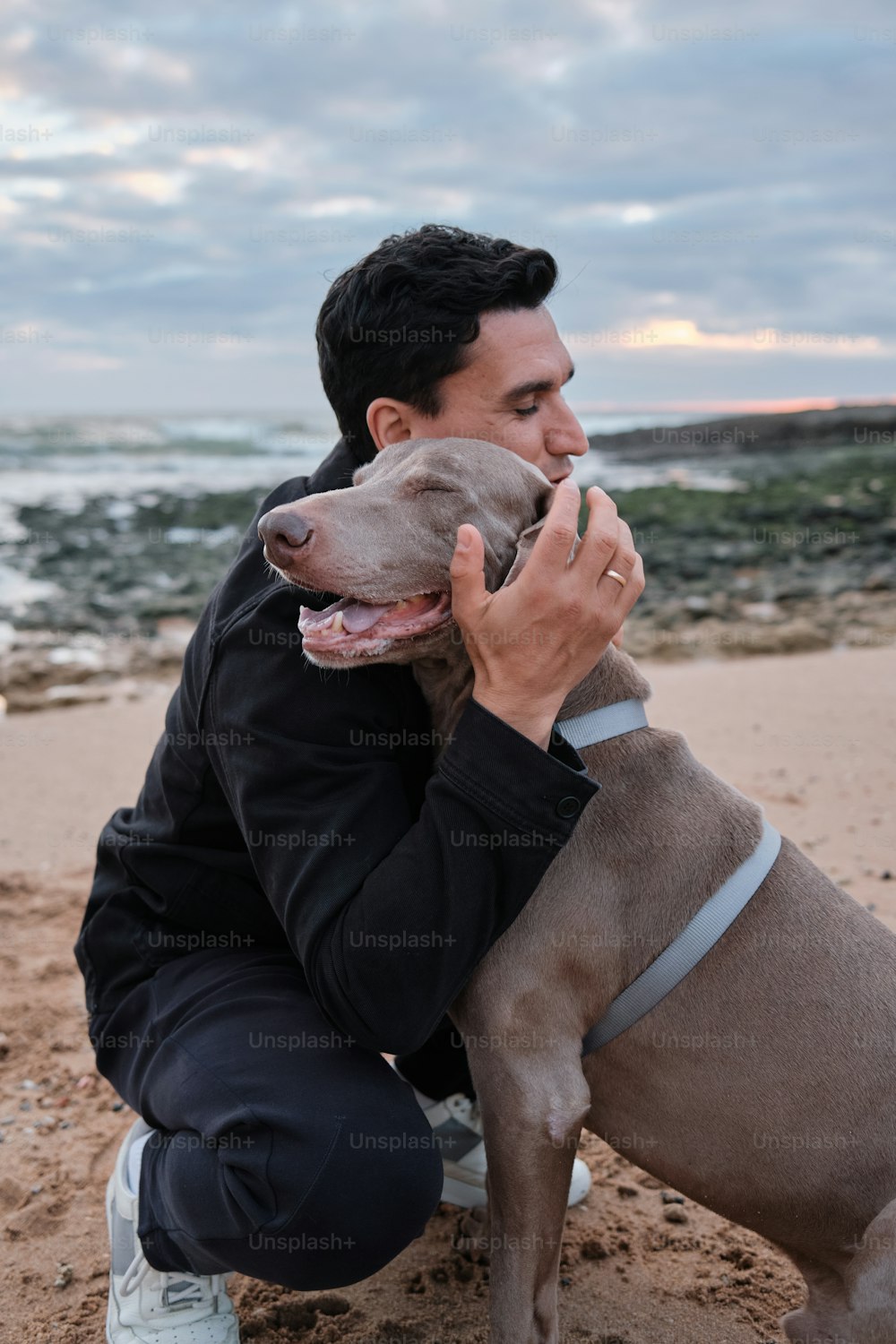 a man holding a dog on the beach