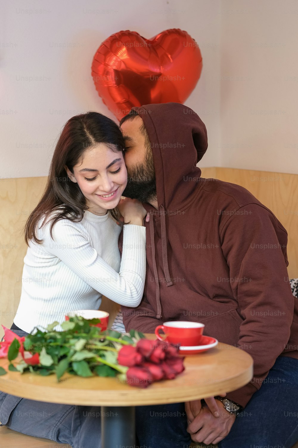 um homem e uma mulher sentados em uma mesa com um balão em forma de coração