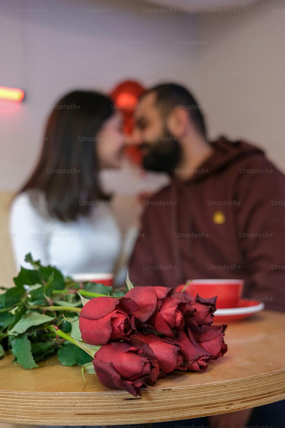 um homem beijando uma mulher enquanto está sentado em uma mesa