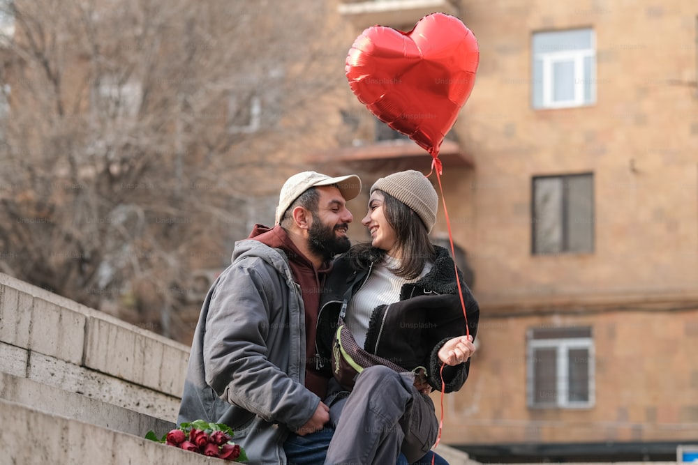 a man and a woman holding a heart shaped balloon