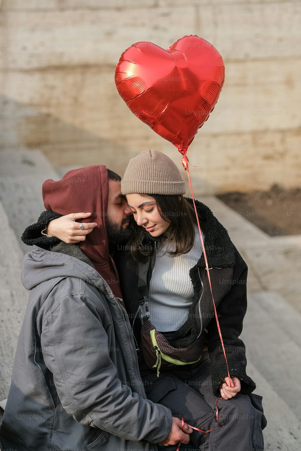 a man and a woman holding a heart shaped balloon