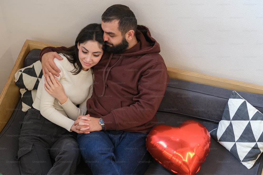 Un homme et une femme assis sur un canapé avec un ballon en forme de cœur