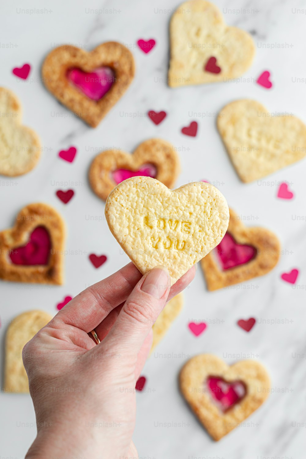 a person holding a heart shaped biscuit in their hand